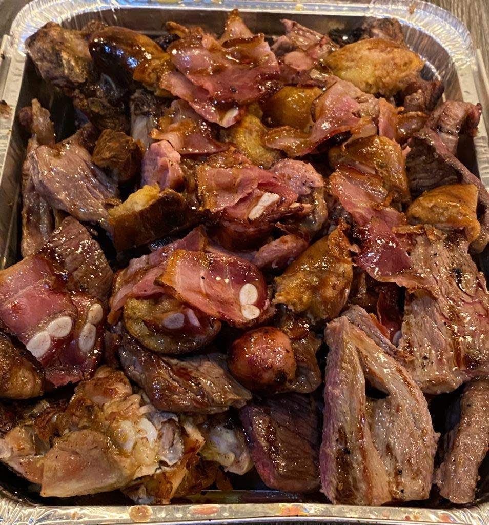 Tabuleiro de alumínio de take away cheio de carnes assadas e entrecosto.